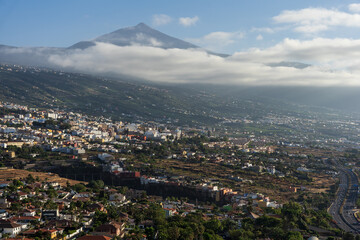 View over Orotava Valley with city buildings, highway and Mount Teide partly covered by clouds from Humboldt Viewpoint, Tenerife, Canary Islands, Spain.
