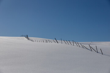 Landscape with snow-covered hills and windbreak fence