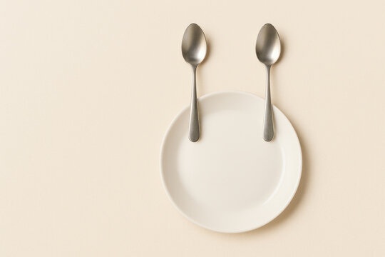 Plate with tablespoons creating a funny face. Space for text.