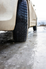 dirty car tire on a bad road covered with solid ice in the off-season