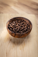 A detailed close-up view of freshly roasted coffee beans in a bowl, showcasing their rich color and texture