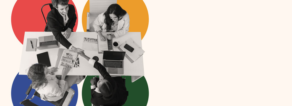 Group of professionals participate in a meeting around a table, discussing ideas while sharing documents and using laptops.