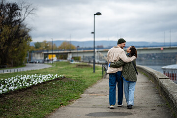 Loving couple embracing walking along river promenade