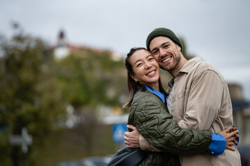 Happy interracial couple embracing in city park