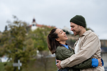Fototapeta premium Happy multiracial couple embracing outdoors and laughing