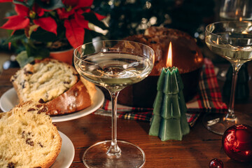 Two elegant champagne glasses filled with bubbly drink, placed on wooden table, with a beautifully decorated Christmas tree in the background