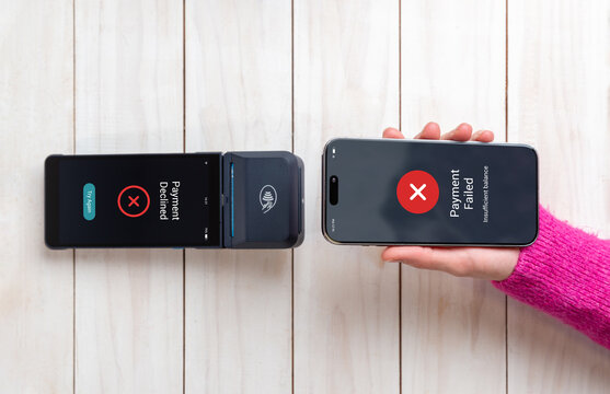 POS terminal and smartphone display matching payment failure alerts after an unsuccessful NFC tap-to-pay attempt on a wooden retail counter