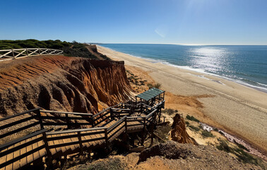 Naklejka premium A wooden staircase with handrails leads to the ocean.