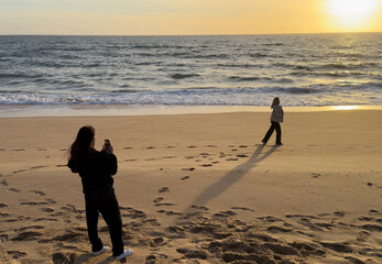 Tourist woman with camera take travel picture on beach at sunset.