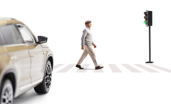 Full length profile shot of a man crossing a street and vehicle stopping at traffic lights