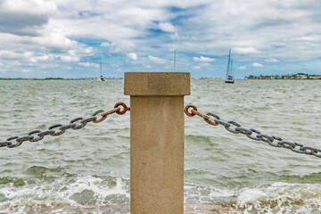 Urban shoreline barrier featuring concrete bollard and steel chain