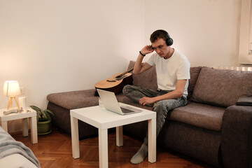 A man puts on headphones while getting ready to use his laptop. The concept highlights focus and digital work in a calm home setting.