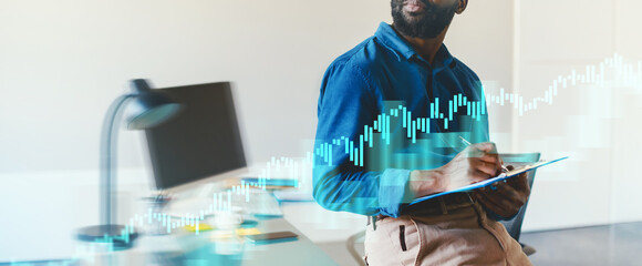 A business professional sits in a modern office, analyzing market trends on a digital tablet while surrounded by graphics and data visualizations, focusing on growth and strategies.