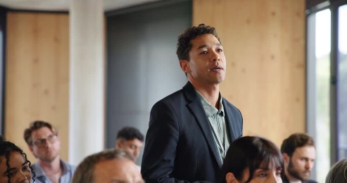 Corporate, seminar or man in crowd with question, information or speech insight at expo. Interaction, asking and business employee at trade show with standing, engagement and feedback at conference.