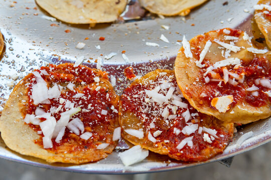 Mexican chalupas with red salsa, onion and cheese