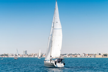 Sailing yacht in Mediterranean sea with Larnaca city on background. Cyprus