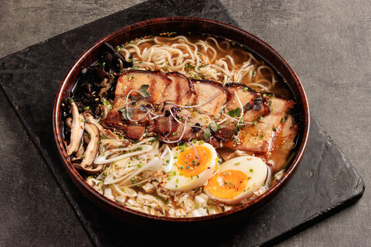 traditional japanese ramen bowl with pork belly, soft-boiled eggs and fresh vegetables