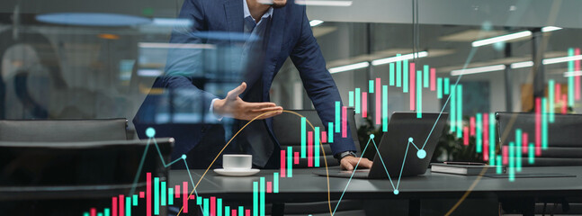 A handsome young middle eastern businessman walks by a modern office, emotionally engaged in a video call. He gestures and smiles while looking at the computer screen, conveying a dynamic discussion.