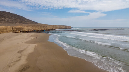 Aerial view of Puerto Eten in Chiclayo, Lambayeque, showing the fishing pier, sandy beach, and calm Pacific coastline under clear skies