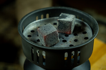 Lump of charcoal on a grill ready for cooking food indoors in the evening