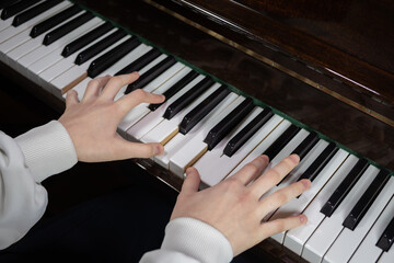 Hands play piano keys in a quiet room during daytime, showing focus and skill in music creation