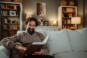 Fototapeta premium Happy man relaxing on sofa reading a book