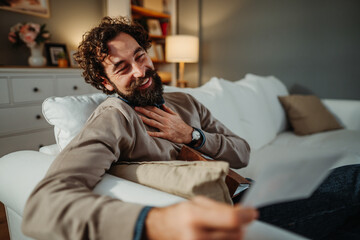 Man laughing on sofa remembering happy moments