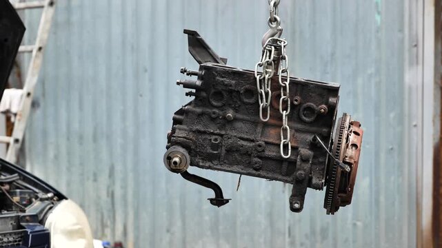 Car engine block hanging from a chain for repair