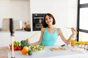 Fotobehang Muziek A young woman smiles while holding a measuring tape in a vibrant kitchen filled with fresh produce. She promotes healthy eating and fitness as she prepares a nutritious meal.  © Prostock-studio