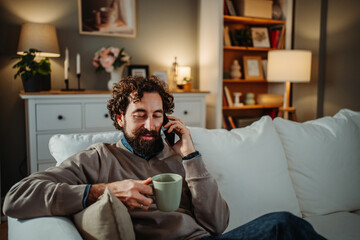 Man relaxing on sofa making phone call