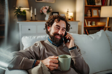 Man smiling having phone call relaxing on couch