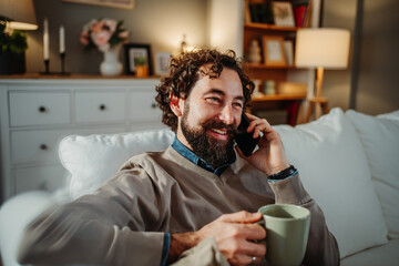 Man talking on phone, drinking coffee in living room
