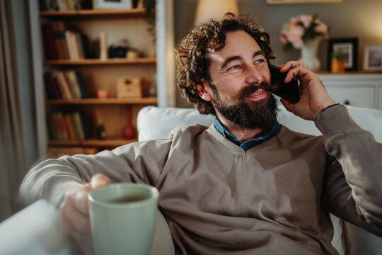 Man relaxing at home, talking on phone
