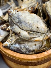 Close-up of dried fish stacked in a wooden container at a market, showing texture, scales and traditional food preservation methods.