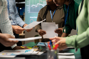 Diverse project team meeting after hours to share data visualization reports, discuss business intel and prepare forecasts for upcoming presentations to enterprise shareholders after hours.