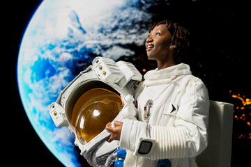 Obraz premium Pleased orbital station astronaut holding helmet amazed by beauty of planet in space. Joyful woman wearing cosmonaut gear astonished by galaxy celestial bodies during planetary exploration mission