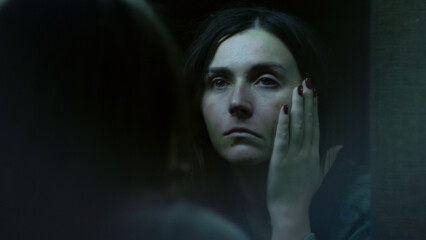 A young woman stares at her reflection in the mirror with confusion and disappointment. A tense emotional moment showing self-doubt, inner struggle, and vulnerability. 