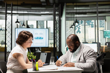 Male job applicant signing the new work contract after being accepted into the organization, HR professional ensuring the onboarding process with employment paperwork and legal terms.