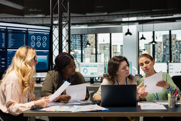 Group of empowered businesswomen collaborate in a modern office, reviewing data, performance indicators and project reports. Demonstrate strategic thinking and corporate feminism.