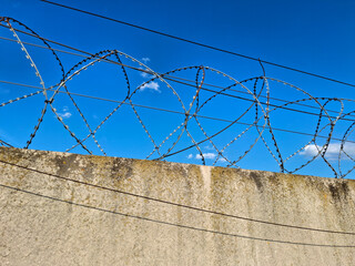 Metal barbed wire is stretched on a concrete fence