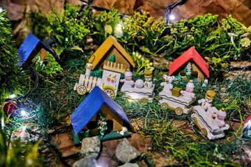 Handmade Christmas decorations featuring colorful miniature houses, snowmen, and a train, creating a festive nativity scene with vibrant details and enchanting ambiance