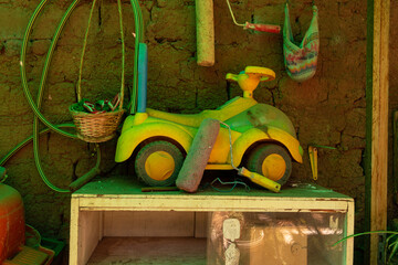 Baby toy stroller on table in small storage room, with things hanging behind it.