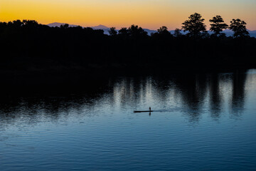 Sunshine Morning Silhouette of a Small Local Fishing Boat on a Calm River Landscape in Southern Laos