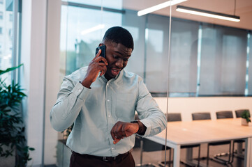 Businessman talking on phone checking time in office