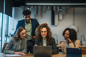 Diverse business team collaborating on laptop during office meeting