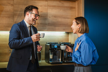 Business colleagues laughing enjoying coffee break in office