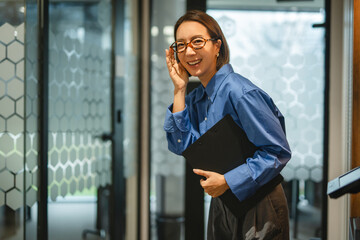 Asian businesswoman smiling holding folder in modern office