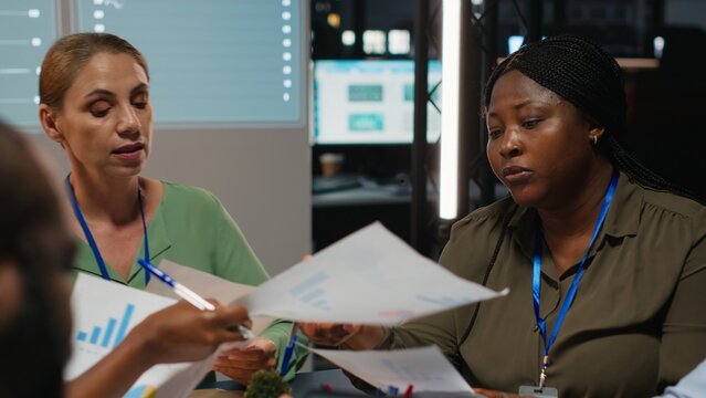Close up of diverse business team meeting after hours for visual data reports, reviewing infographics and projections while sharing files to establish finance objectives. Business intel. Camera B. - Powered by Adobe