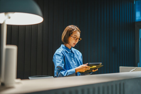 Woman designer reading sample book in modern office