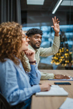 Business man raising hand asking question during meeting